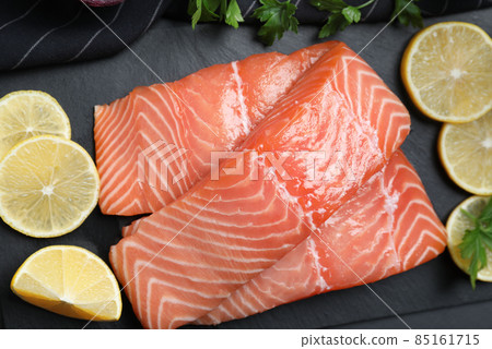 Top view of fresh raw salmon with lemon and parsley on slate plate. Fish delicacy 85161715