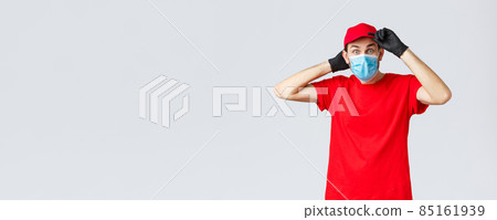 Groceries and packages delivery, covid-19, shopping concept. Excited surprised delivery man in red uniform, fix cap on head and staring interested camera, courier on duty during coronavirus Groceries and packages delivery, covid-19, shopping concept. Excited surprised delivery man in red uniform, fix cap on head and staring interested camera, courier on duty during coronavirus 85161939