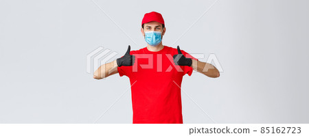 Covid-19, self-quarantine, online shopping and shipping concept. Friendly courier in face mask and gloves, recommend contactless delivery, avoiding touch, no contact send packages, thumb-up 85162723