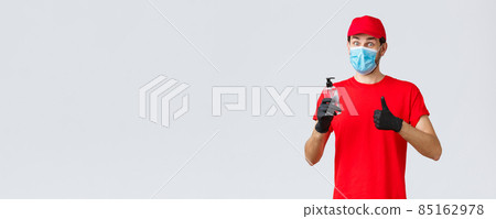Takeaway, food and groceries delivery, covid-19 contactless orders concept. Courier in red uniform cap, medical face mask and gloves, recommend using hand sanitizer or soap 85162978