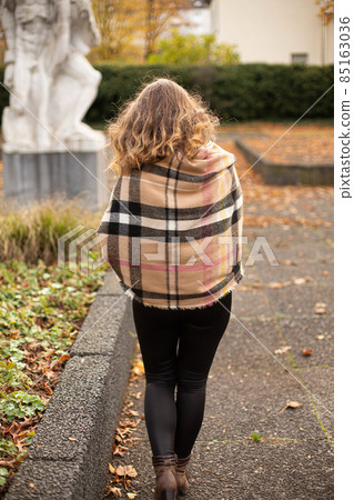 Young woman in warm scarft walking in autumn 85163036