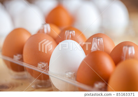 Close-up view of raw chicken eggs in egg box on wooden background Close-up view of raw chicken eggs in egg box on wooden background 85163371
