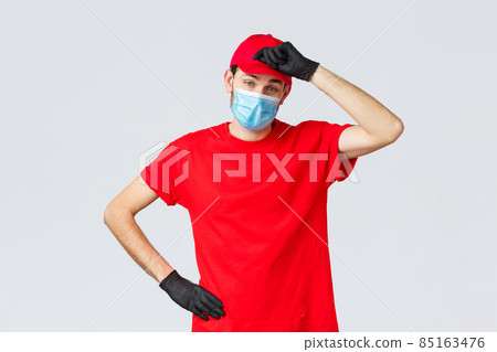 Covid-19, self-quarantine, online shopping concept. Delivery guy wiping sweat from forehead as tired of carry heavy packages to clients, working in coronavirus outbreak, wear face mask and gloves 85163476