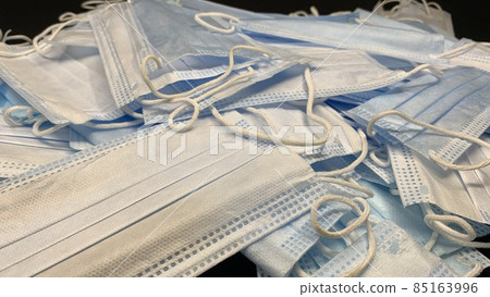 Medical masks in large numbers are scattered on a black table Medical masks in large numbers are scattered on a black table 85163996