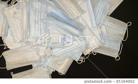 Medical masks in large numbers are scattered on a black table 85164002