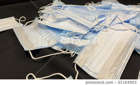 Medical masks in large numbers are scattered on a black table 85164003