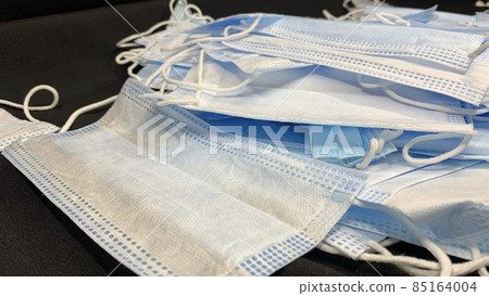 Medical masks in large numbers are scattered on a black table 85164004