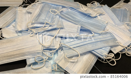Medical masks in large numbers are scattered on a black table 85164006