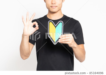 A man in a black T-shirt standing in front of a white background and showing a beginner's mark 85164096