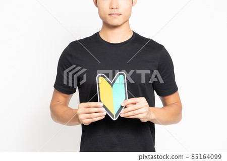 A man in a black T-shirt standing in front of a white background and showing a beginner's mark A man in a black T-shirt standing in front of a white background and showing a beginner's mark 85164099