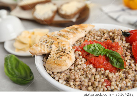 Tasty buckwheat porridge with meat and vegetables in bowl, closeup 85164282