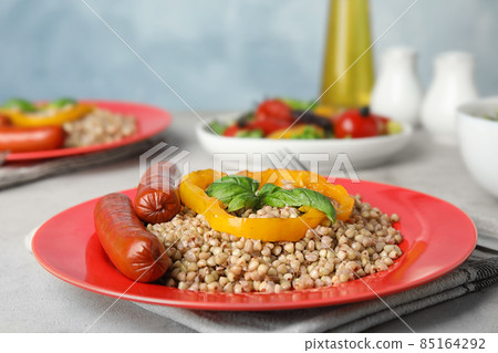 Tasty buckwheat porridge with sausages on light table. Space for text 85164292