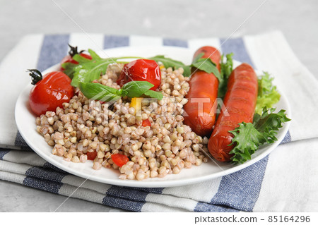 Tasty buckwheat porridge with sausages on table, closeup 85164296