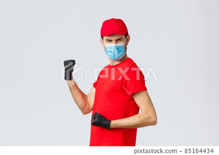 Covid-19, self-quarantine, online shopping and shipping concept. Energized, excited delivery guy do champion dance, fist pump and looking empowered, celebrate success, rejoicing in courier outfit 85164434