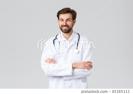 Hospital, healthcare workers, covid-19 treatment concept. Successful professional doctor in white scrubs with stethoscope, cross arms chest and smiling, working at clinic, help patients 85165111