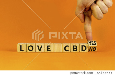 Love CBD, cannabidiol symbol. Doctor turns a cube and changes words 'love CBD no' to 'Love CBD yes'. Beautiful orange background, copy space. Medical and love CBD cannabidiol concept. 85165633