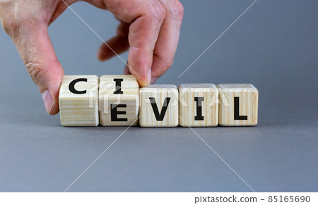 Civil or evil symbol. Male hand flips wooden cubes and changes the word 'evil' to 'civil'. Beautiful grey background, copy space. Business and civil or evil concept. 85165690