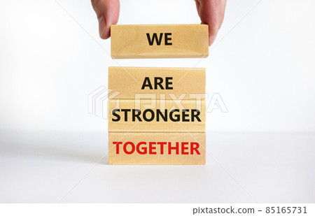 We are stronger together symbol. Concept words We are stronger together on wooden blocks. Businessman hand. Beautiful white background, copy space. Business and we are stronger together concept. 85165731