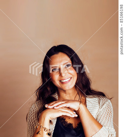 pretty brunette confident mature woman posing cheerful on warm brown background, lifestyle people concept pretty brunette confident mature woman posing cheerful on warm brown background, lifestyle people concept 85166198
