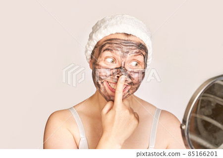 Young woman applying black face mask. Charcoal facial product. Acne and pimple Young woman applying black face mask. Charcoal facial product. Acne and pimple 85166201