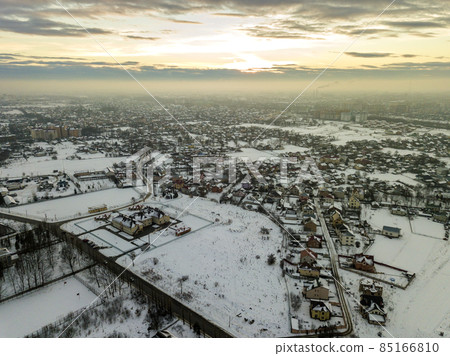 Top view of city suburbs or small town nice houses on winter morning on cloudy sky background. Aerial drone photography concept. Top view of city suburbs or small town nice houses on winter morning on cloudy sky background. Aerial drone photography concept. 85166810