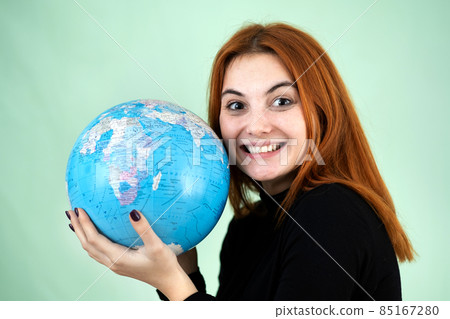 Portrait of a happy young woman holding geographic globe of the world in her hands. Travel destination and planet protection concept. 85167280