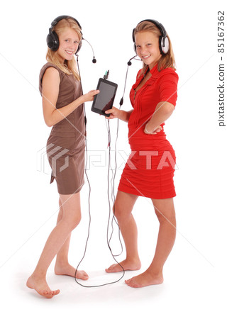 Two pretty teenage girls listening music on her headphones Two pretty teenage girls listening music on her headphones 85167362