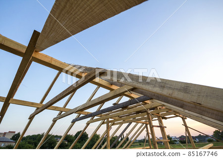 New wooden house under construction. Close-up of attic roof frame against clear sky from inside. Ecological dream home of natural materials. Building, construction and renovation concept. 85167746