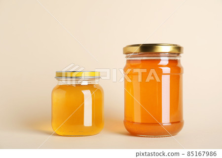 Jars with different types of organic honey on beige background Jars with different types of organic honey on beige background 85167986