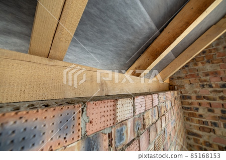 Interior of unfinished brick house with concrete floor, bare walls ready for plastering and wooden roofing frame attic under construction. 85168153