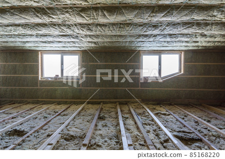 House attic under construction. Mansard walls and ceiling insulation with rock wool. Fiberglass insulation material in wooden frame for cold barrier House attic under construction. Mansard walls and ceiling insulation with rock wool. Fiberglass insulation material in wooden frame for cold barrier 85168220
