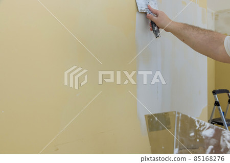 Man plastering the walls with finishing putty in the room with putty spatula 85168276