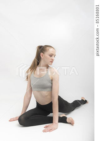 Portrait of strong young fitness woman make yoga stretching exercises on white background. Young girl is doing stretching or gymnastics. Portrait of strong young fitness woman make yoga stretching exercises on white background. Young girl is doing stretching or gymnastics. 85168801