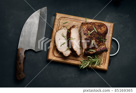 baked piece of pork meat in spices on a wooden board, cut into pieces baked piece of pork meat in spices on a wooden board, cut into pieces 85169365