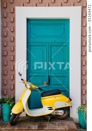 yellow motorcycle at the turquoise wooden door 85169471
