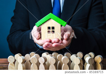 A man presents a house to people. Offer an affordable mortgage loan for home purchase. State guaranteed housing. Providing social real estate for people in need. Rent of apartments and houses. 85169715