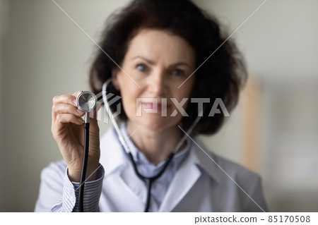 Mature female GP doctor hand holding stethoscope close up object 85170508