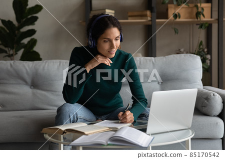 Latin woman in earphones study online on laptop 85170542