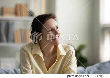 Happy positive mature 50s woman sitting on sofa at home 85170856