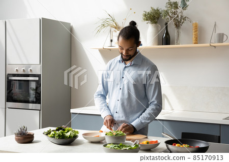 Happy young African American man cooking in modern kitchen. 85170913