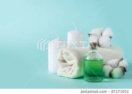 Aromatherapy wellness concept. Spa and relaxation accessories on a blue background. Aromatic oil, towel, candle and flowers. Organic skin care product. 85171052