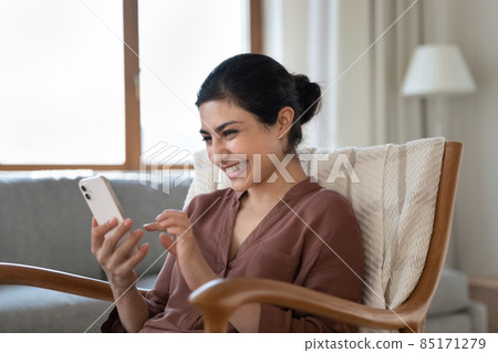 Happy young indian woman laughing looking at smartphone screen. Happy young indian woman laughing looking at smartphone screen. 85171279
