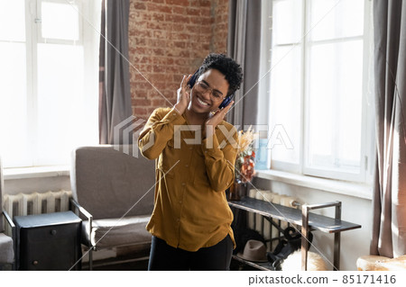 Happy young African American woman listening music in headphones. 85171416