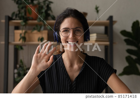 Millennial latin female in earphones talk to webcam wave hand Millennial latin female in earphones talk to webcam wave hand 85171418
