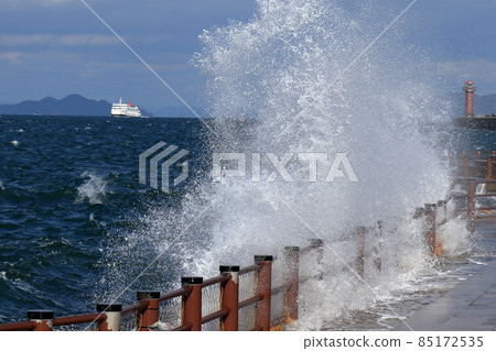 Strong wind waves, big waves splashing in the Seto Inland Sea, hazy red lighthouse 85172535