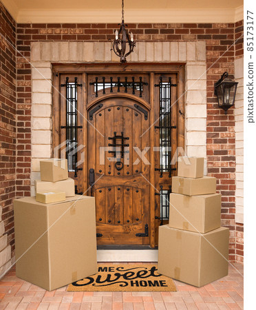 Several Packages Sitting on Home Sweet Home Welcome Mat At Front Door of House. 85173177