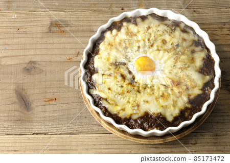 A bird's-eye view of a freshly baked curry with plenty of melted cheese and eggs A bird's-eye view of a freshly baked curry with plenty of melted cheese and eggs 85173472