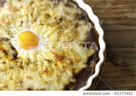 A bird's-eye view of a freshly baked curry with plenty of melted cheese and eggs A bird's-eye view of a freshly baked curry with plenty of melted cheese and eggs 85173482