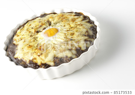 A freshly baked curry with plenty of melted cheese and eggs on a white background 85173533