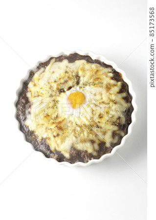 A bird's-eye view of a freshly baked curry with plenty of melted cheese and eggs on a white background 85173568
